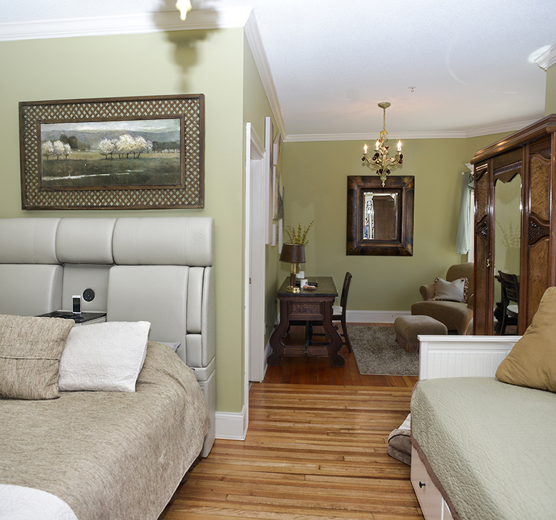 A guest room with a crystal chandelier, zebra chair, and vintage furnishings